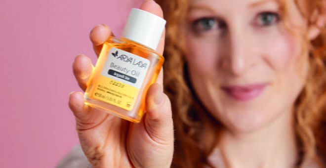 Eine Frau hält ein Beauty Oil in die Kamera