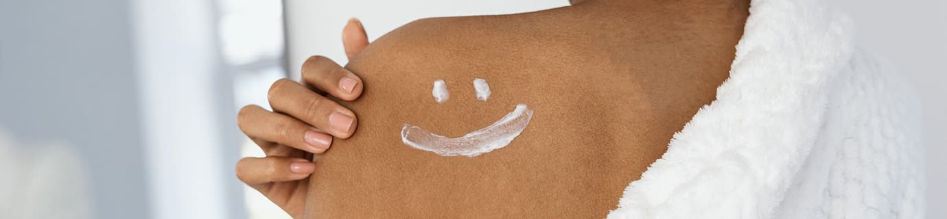 Frau hat sich mit Body Lotion einen Smiley auf die Schulter gemalt