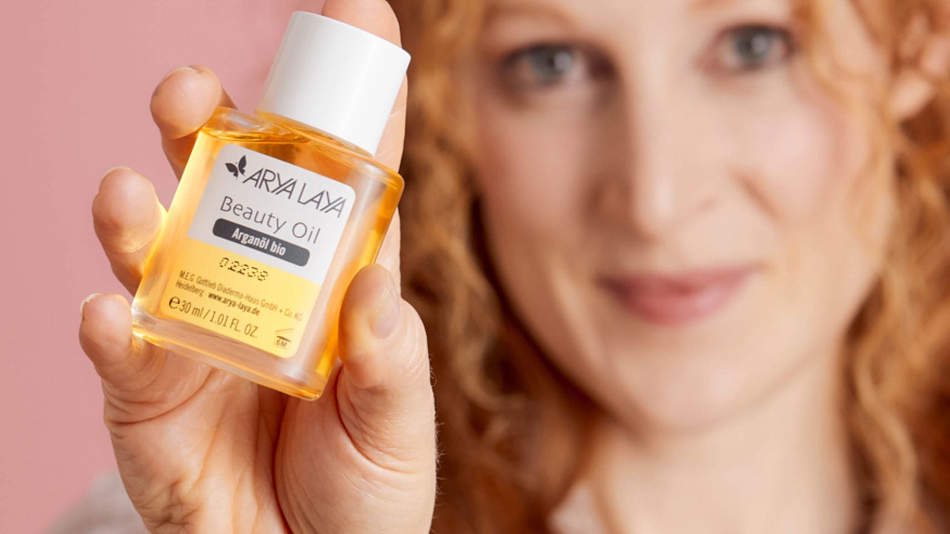 Eine Frau hält ein Beauty Oil in die Kamera