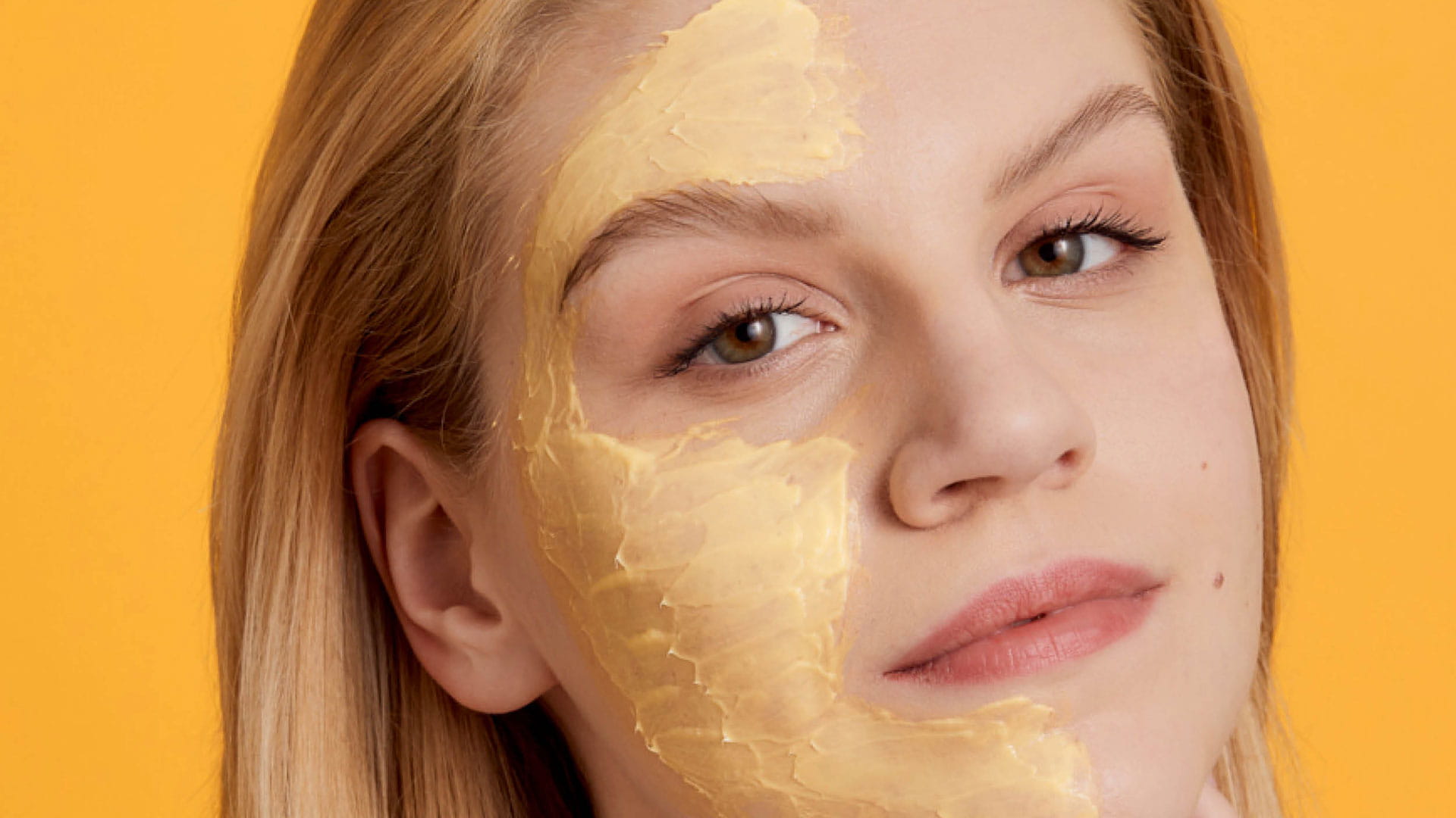 Header Masken und Balsam Produktgruppe Eine Frau hat auf der einen Gesichtshälfte eine Maske aufgetragen